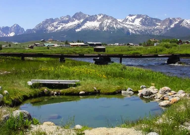 Snake Pit Hot Springs natural soaking pools along creek with Sawtooth Mountains in background near Stanley Idaho